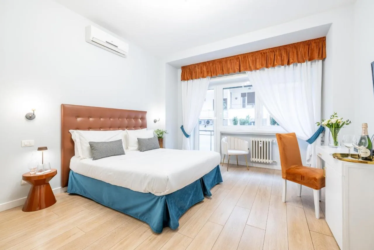 Double room with a terracotta headboard, white linens and a window onto the street