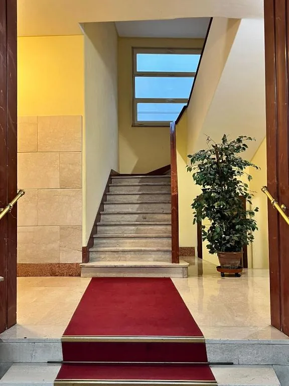 Entrance hall with a marble staircase and a red carpet